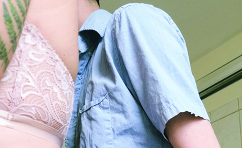 Photo of two pale figures, one in lacy underwear and bra, the other with a hand on their waist, fully clothed.