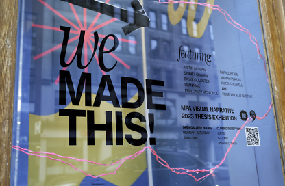 A blue window display that features the Thesis exhibition with names of the graduating class.