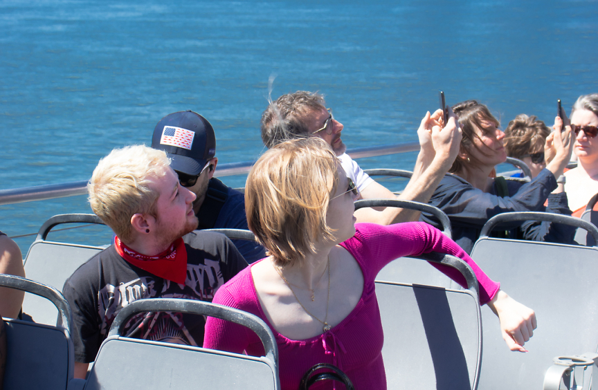 A group of students sit on a boat on the East River in New York.