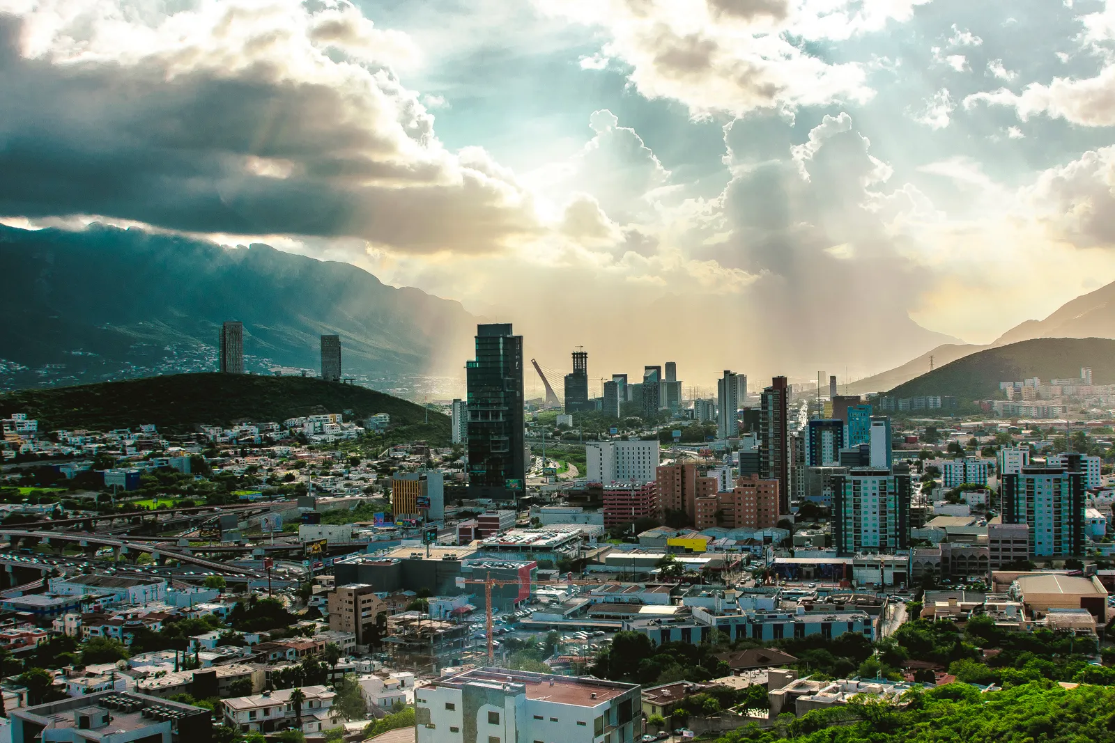 Panoramic view of a large city with skyscrapers and large mountains that loom over the city.