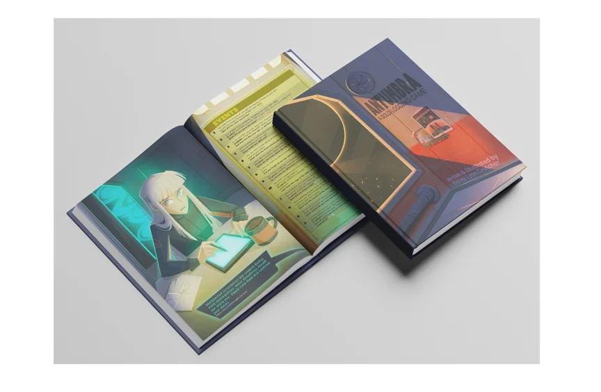 Photo of the printed Antumbra book mock-up, open to show colorful illustrated interior spreads.